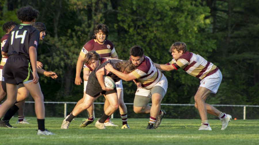 Sophomore Ian Schurman and junior Jack Cheney work together to tackle an opposing player during the rugby game on May 11. Boys’ rugby beat Blue Hills 33-10.
