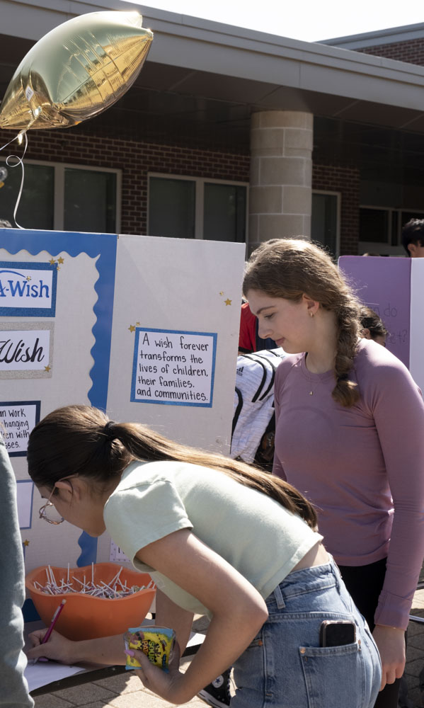 Senior Allison Moore watches over a new member signing up for the Make A Wish club.