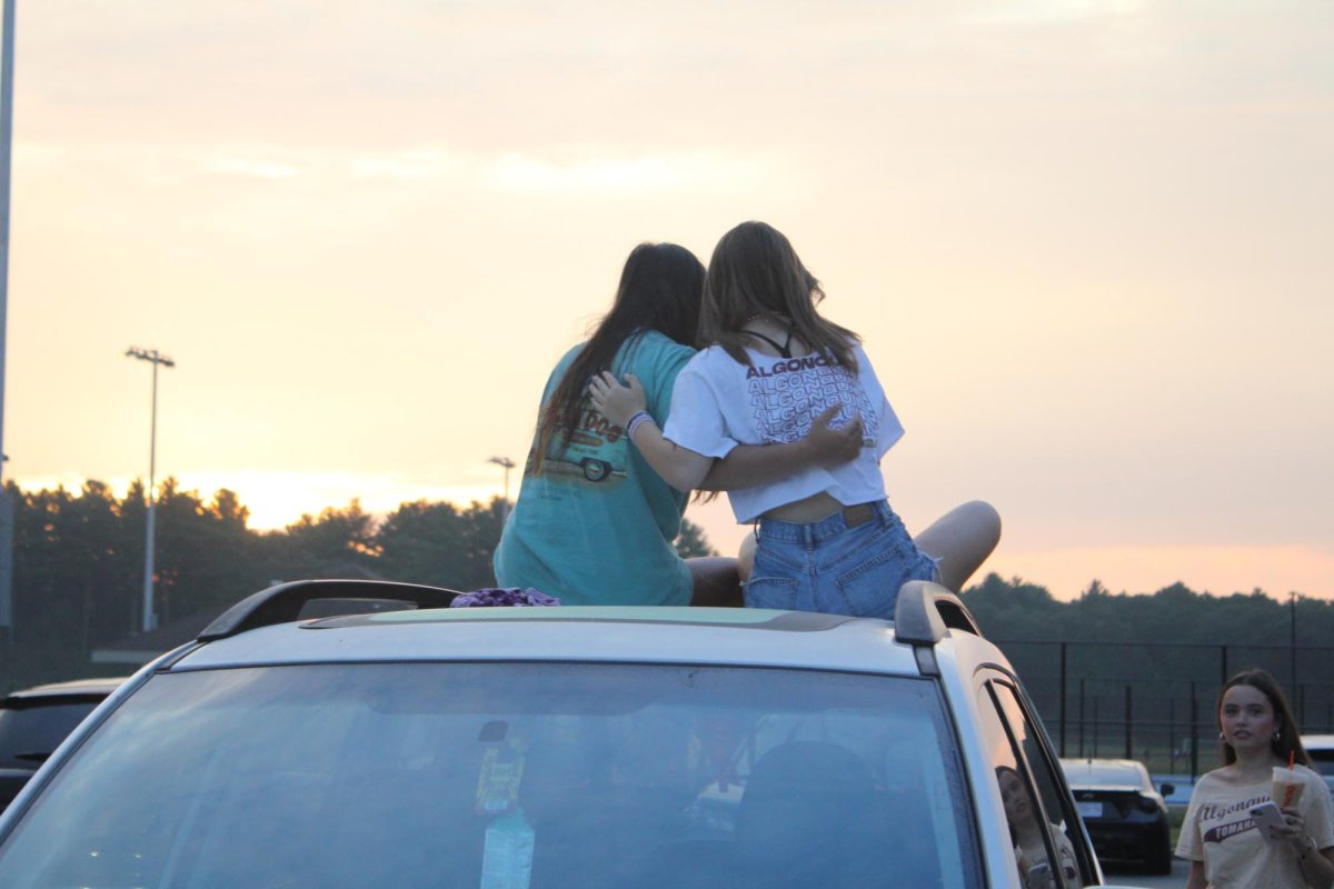 Seniors Ellie Ouano and Olivia Mullen pose on top of a car for Senior Sunrise.