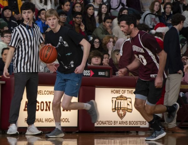 Senior Yates Campbell dribbles past math teacher Patrick Galvin at the Student-Faculty basketball game held on Dec. 22, 2023; the faculty won the game 38-34.