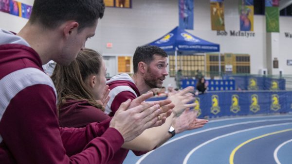 Math teacher and track coach Patrick Galvin cheers for Algonquin runners at the Northeast Invitational on Jan. 12, 2024. Accompanied by math teacher Corey Pooler, the teachers coach the runners on the track and teach them in the classroom.