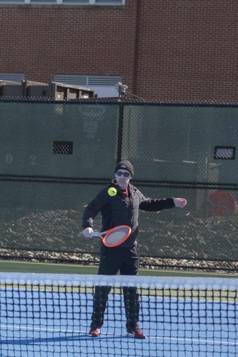 At the girls' tennis tryouts on March 18, new coach Dan Welty shows the team how the first activity will be done and what to do.