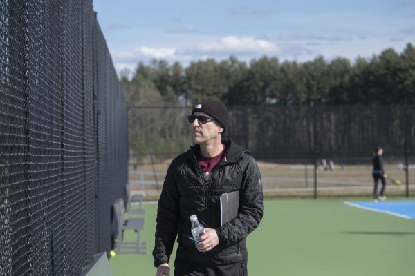 At the girls tennis tryouts on March 18, new coach Dan Welty observes the girls practicing on the adjacent court.