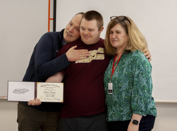 Postgraduate William Iverson smiles with his parents after receiving his diploma on April 1, 2024.