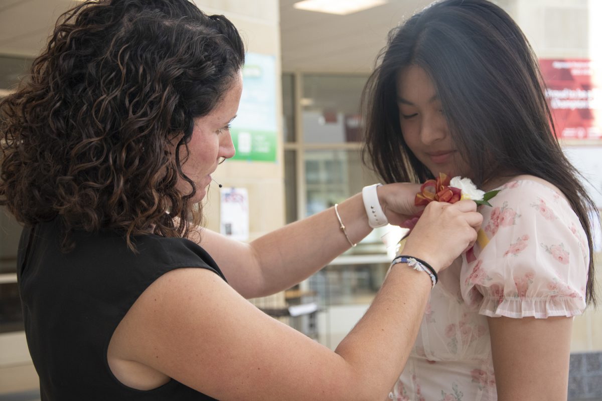 Wind Ensemble and Orchestra Director Amy Collins pins flowers on senior Angelina Zhang before Zhangs performance at POPS Night on May 29.