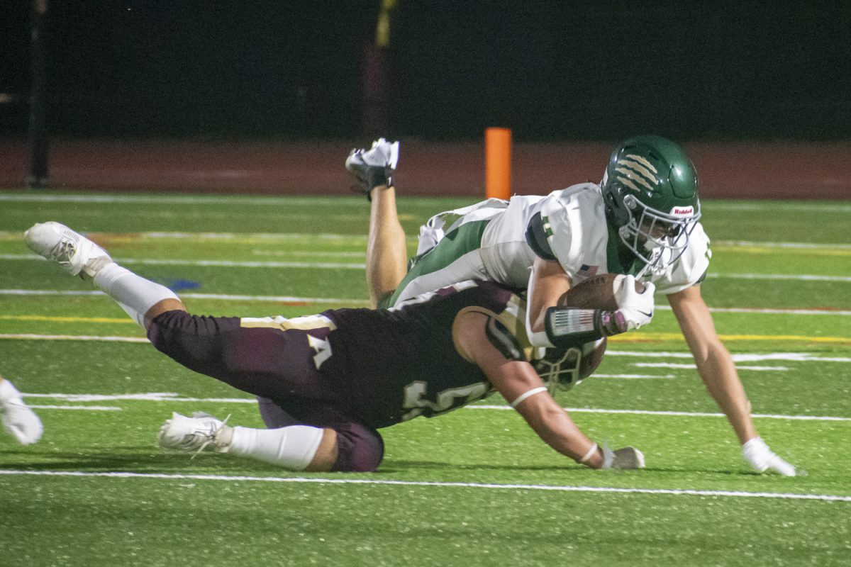 Senior captain Dom Frallicciardi (55) tackles a Nashoba player during the first football game on Sept. 6. Algonquin beat Nashoba 19-7.