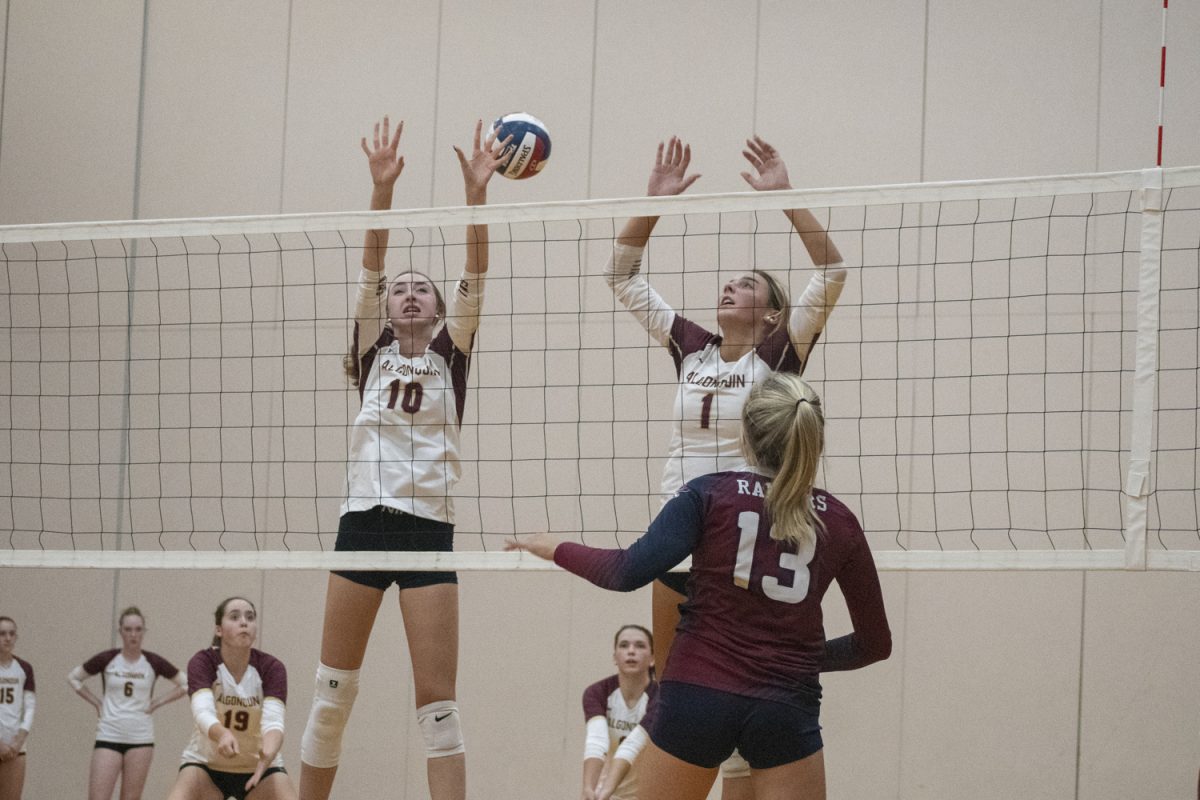 During their 0-3 loss against Westborough, junior Tessa Novello (left) and senior Grace Chiota (right) attempt to block a spike from a Westborough opponent on Sept. 17.