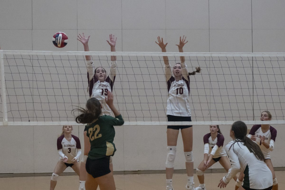 During Algonquin's 3-0 girls' volleyball win, junior Tessa Novello (10)  and senior Ella Poultney (19) jump to block the ball on Oct. 4.