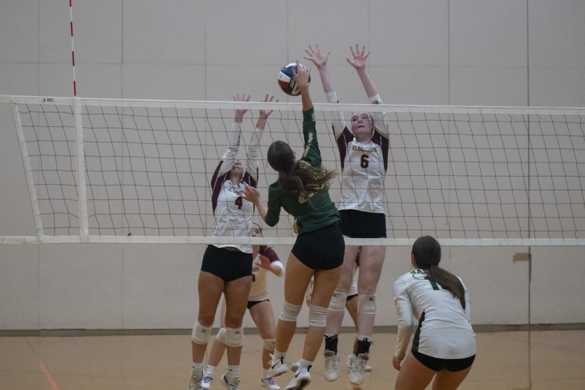 Junior Niki Chacharone (left) and senior Katy O'Connell (right) jump up to block the ball during Algonquin's girls' volleyball win on Oct. 4.