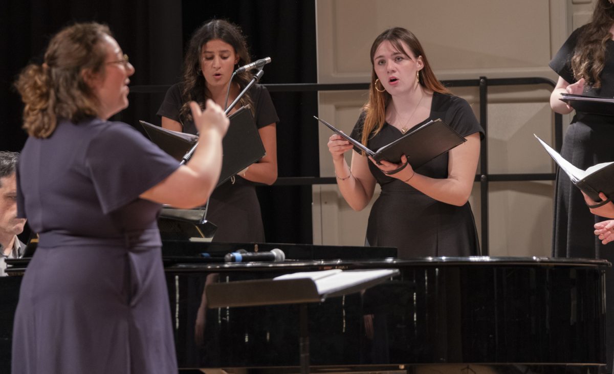 Senior Mira Denney looks at music teacher Olivia Goliger during Chamber Choir's performance of “Jubilate Deo” at the Songs for the People choral concert on Oct. 22.