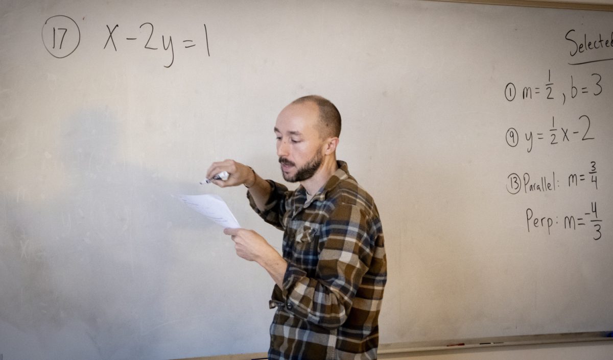 Christian Austin, a new math teacher at Algonquin, demonstrates a problem from the previous night’s homework. Austin performs the problem on a whiteboard, going step by step for his class.