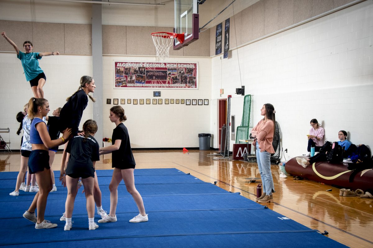 Catherine Drake, the cheerleading coach, watches as cheerleaders are lifted up during practice on Oct. 24.