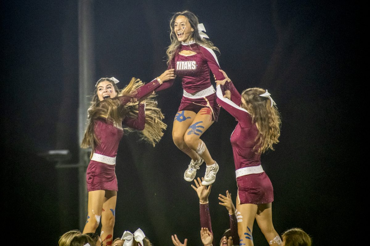 Senior captain Julianna Craver is hoisted into the air during the cheer team's halftime performance during the Sept. 27 football game.