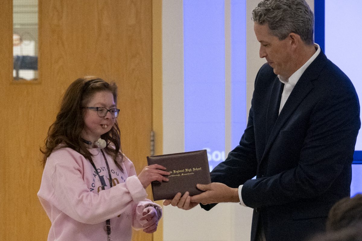 Principal Sean Bevan hands graduate Julia Cobb her diploma, celebrating her graduation on Nov. 26.