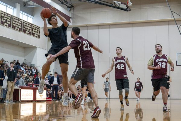 Senior Ryan Roman jumps to shoot as math teacher Patrick Galvin tries to block him during the annual student-faculty basketball game.