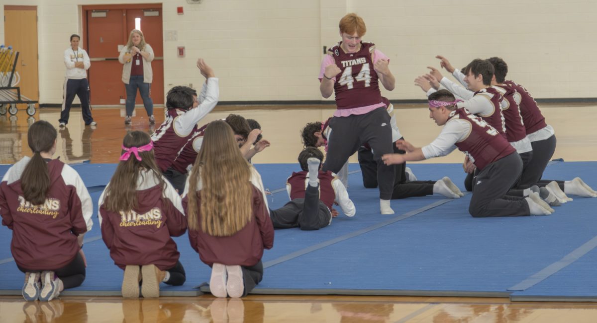 The varsity football team, along with the cheer team, watches and bows to senior Owen Ellsworth as he dances for the 2024 pep rally, circling around him.