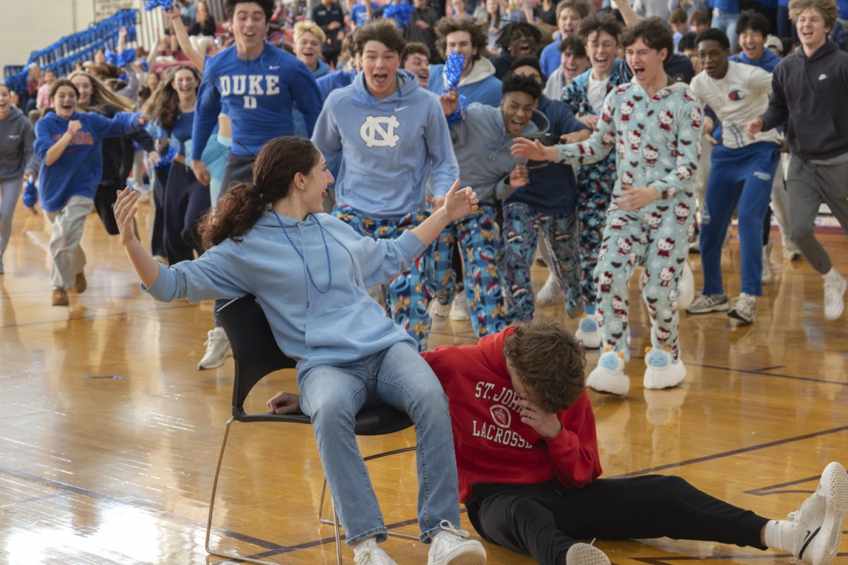 Junior Nina Boeckeler celebrates her victory in musical chairs as members of the junior class rush onto the gym floor, cheering for her during the 2024 pep rally.