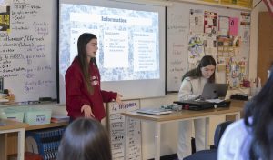 During the bi weekly meeting of the French Honor Society on March 27th, junior Laura White talks about the meeting's agenda while junior Altea Mehillaj takes attendance.