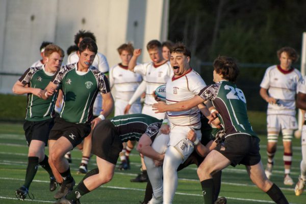 Junior Mike Montalvo carries the ball down the field as Marshfield players attempt to tackle him during their April 17 match. The Titans won 34-0.