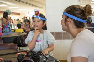 Student Cathy plays "Headbands" with junior Sophia Lalau. Cathy asks Lalau questions about the card on her head during the International Night at Algonquin on May 16.