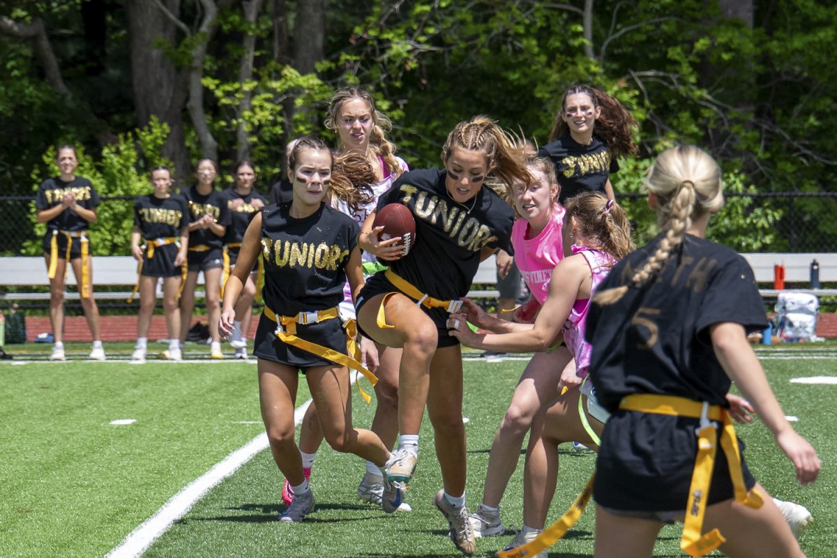 At the Powderpuff game on May 19, junior Delaney Walker runs past the seniors while they attempt to pull off her flag belt. The juniors won the Powderpuff game 12-6.