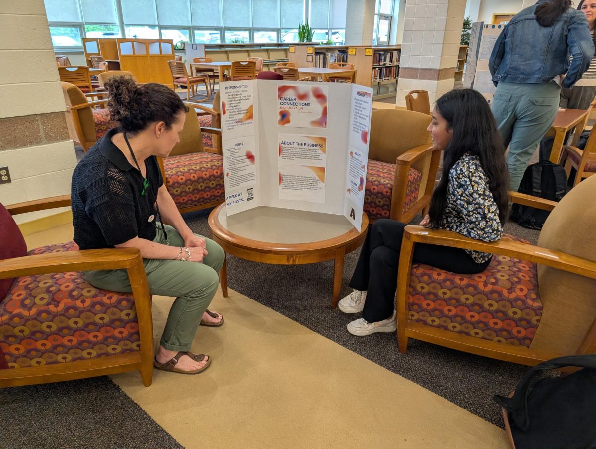 Senior Sumeru Achar share the insights of her internship at Firefly Coders with a fellow community member on May 15 in the ARHS Library. Eleven juniors and seniors participated in various internships across the community during the 24-25 school year and then highlighted their learnings at the showcase. 