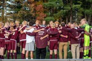 The boys soccer team embraces before their playoff game with their bleached hair. This team tradition was started by English teacher and former coach John Frederick and aimed to create a sense of community and collaboration. 