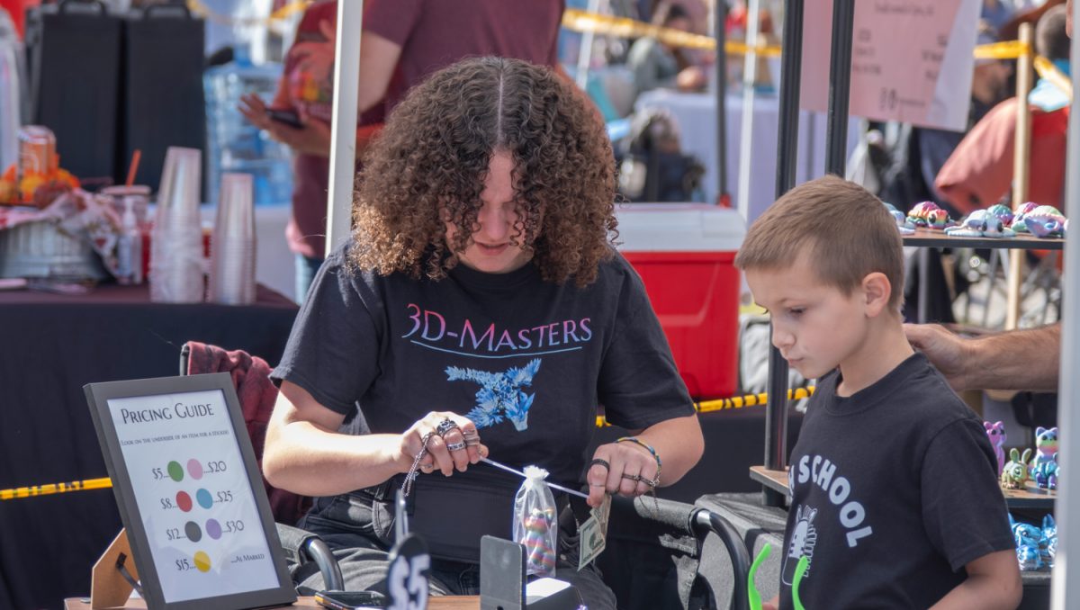 At the 35th annual Applefest on Sept. 20, freshman Brooke Robinson packs a young customer's purchase at the 3D-Masters booth run by her and her dad.