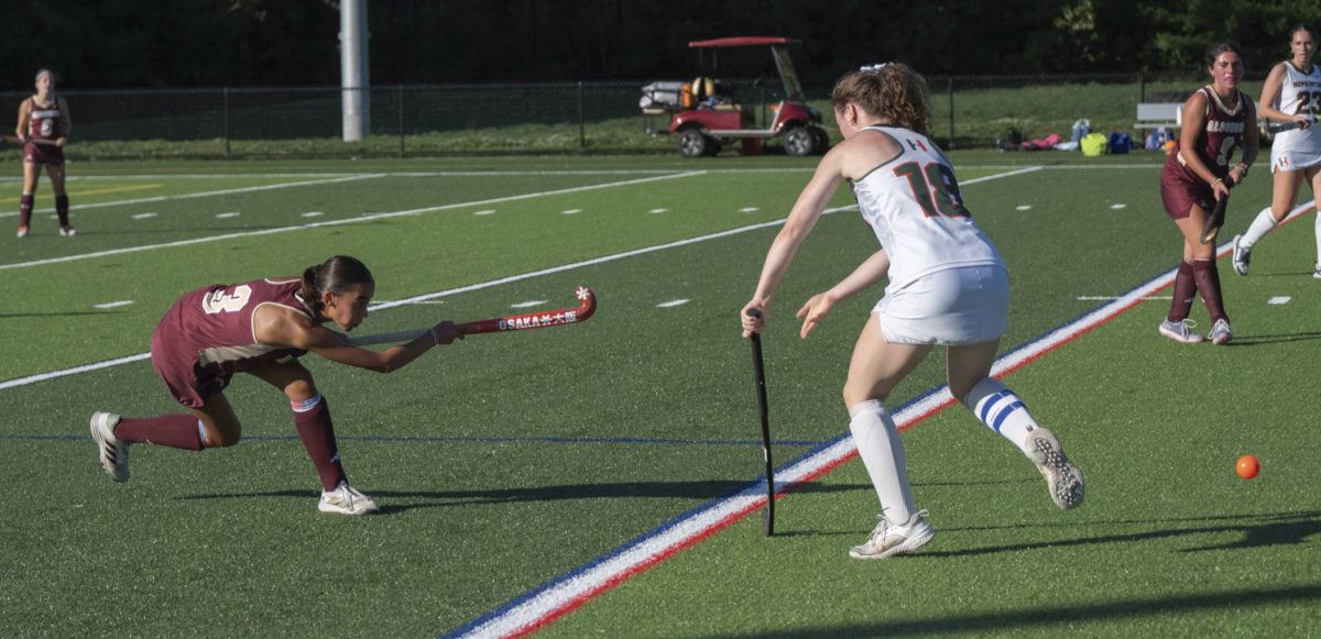 During the first quarter of the field hockey game on Sept. 26, junior Hannah Regan hits the ball away from an opponent. 