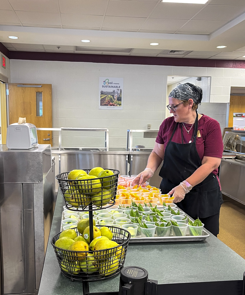 Before the lunch period on Sept. 8, cafeteria staff Andrea Campbell lays out a tray of orange slices. Portioned fruits and vegetables are among the cafeteria’s newest options for side dishes.