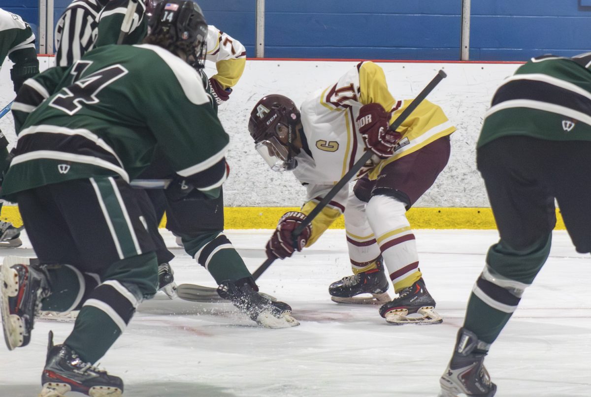 Senior Gilbert Prepetit gets the puck after a face-off during the boys’ hockey game against Wachusett on Jan. 14.