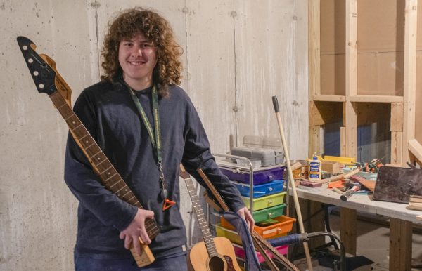 Junior Nick Simoneau holds a couple of the necks for his guitar projects in his basement workshop.