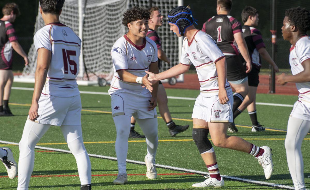 Senior Jordyn Reyes highfives sophomore Brody Lynch after he scores during the boys’ rugby game against Chelmsford on May 28.
